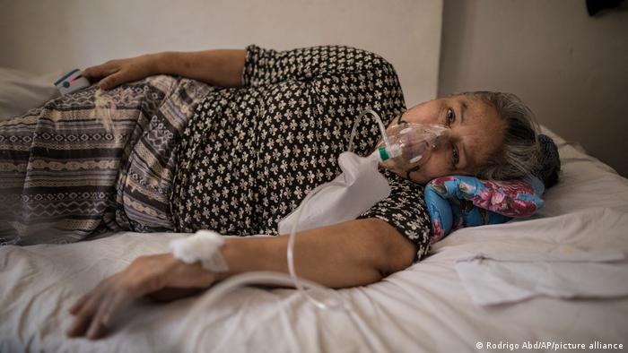 Elena Ruiz, de 53 años, respira oxígeno con la ayuda de una enfermera, como parte del tratamiento de recuperación de COVID-19, en Lima, Perú.