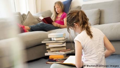 Zwei Mädchen lesen in einem Stapel Bücher