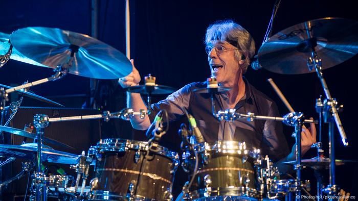 Stewart Copeland wearing a headband while playing drums. 