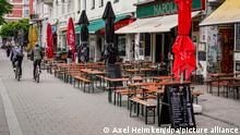Radfahrer fahren an den aufgestellten Tischen und Bänken vor Restaurants des Hamburger Schanzenviertels vorbei. Außengastronomie und Einzelhandel dürfen in Hamburg unter Auflagen wieder öffnen. +++ dpa-Bildfunk +++