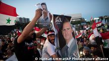 Injured Syrian soldiers supporters of President Bashar Assad hold up national flags and pictures of Assad as they celebrate at Omayyad Square, in Damascus, Syria, Thursday, May 27, 2021. (AP Photo/Hassan Ammar)