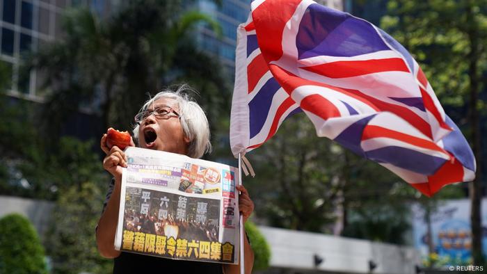 2021年5月黎智英出庭聆訊，一名支持者在法庭外手持蘋果和《蘋果日報》以示抗議。