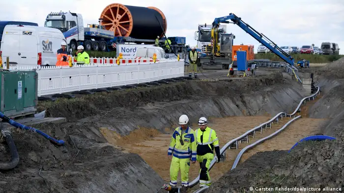 圖片為挪威和德國之間的輸電線路NordLink的電纜鋪設情況。工作人員站在可以看到管道的溝渠中