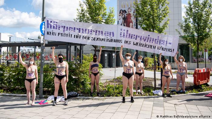 Frauen mit nacktem Oberkörper halten ein Tarnsparent hoch. Auf ihren Körpern steht der Schriftzug „This is reality - not TV“, auf dem Banner: „Körpernormen überwinden - Kein Profit mit der Sexualisierung des weiblichen Körpers“.