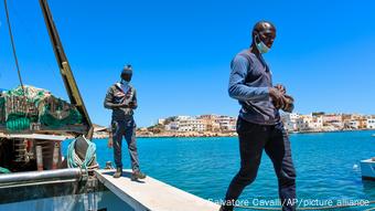 Deux sénégalais débarquent du bateau de pêche Vincenzo Padre sur lequel ils travaillent, sur l'île de Lampedusa dans le sud de l'Italie