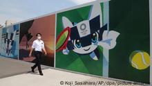 Ein Mann mit Mund-Nasen-Schutz geht an Plakaten vorbei, die für die Olympischen Spiele werben. Am 23. Juli, sollen in der Hauptstadt Tokio die Olympischen Spiele beginnen. +++ dpa-Bildfunk +++