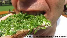 guy bites into bread with spread and chives, vegan snack || Modellfreigabe vorhanden