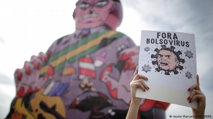 Cartaz pede Fora Bolsovírus em frente a boneco inflável de Bolsonaro com mãos sujas de sangue Cartaz pede Fora Bolsovírus em frente a boneco inflável de Bolsonaro com mãos sujas de sangue