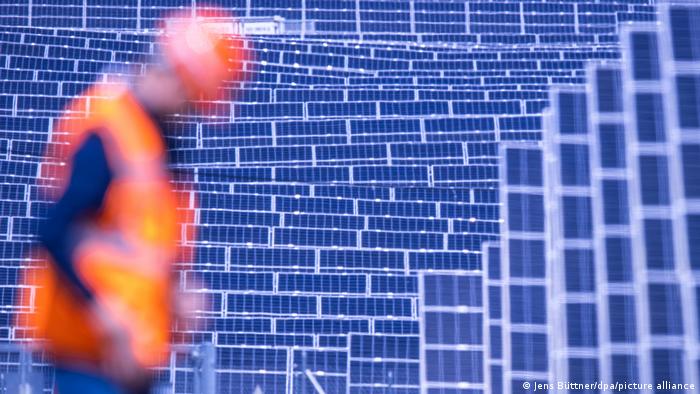 Мужчина в жилете со световозвращающими полосами и солнечная электростанция фирмы Enerparc в земле Мекленбург-Передняя Померания