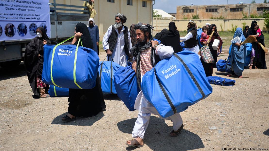Afghan refugees carrying free aid distributed by the IOM