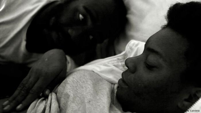 Film still 'Dirty Feathers': black-and-white portrait of two people's faces lying down, one is blurry in the background.