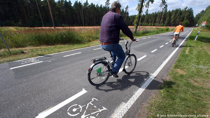 Bikers ride down a bike lane on a country road in Mecklenburg-Western Pomerania, Germany