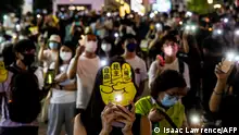 People hold up their phones with the light on in the Causeway Bay district of Hong Kong on June 4, 2021, after police closed the venue where Hong Kong people traditionally gather annually to mourn the victims of China's Tiananmen Square crackdown in 1989 which the authorities have banned citing the coronavirus pandemic and vowed to stamp out any protests on the anniversary. (Photo by ISAAC LAWRENCE / AFP)