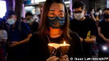 A woman holds candles in the Causeway Bay district of Hong Kong on June 4, 2021, after police closed the venue where Hong Kong people traditionally gather annually to mourn the victims of China's Tiananmen Square crackdown in 1989 which the authorities have banned citing the coronavirus pandemic and vowed to stamp out any protests on the anniversary. (Photo by ISAAC LAWRENCE / AFP)
