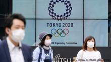 Pedestrians walk past an electric signboard showing the Tokyo Olympics Emblem, in Tokyo, June 3, 2021. The Japanese government told that the government remains committed to holding the games as scheduled. JIJI PRESS PHOTO/MORIO TAGA