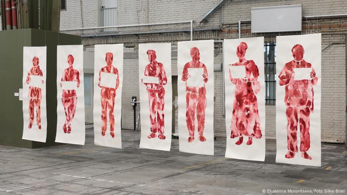 Ekaterina Muromtseva artwork 'Picket': paintings of 7 larger-than-life, blood red figures showing an empty sign.