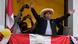 Perus gewählter Präsident Pedro Castillo breitet die Arme aus auf einem mit peruanischer Flagge geschmückten Balkon Perus gewählter Präsident Pedro Castillo breitet die Arme aus auf einem mit peruanischer Flagge geschmückten Balkon