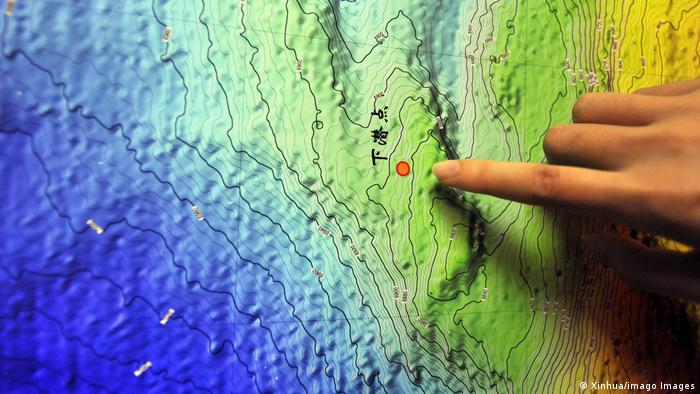 Ein Mensch deutet mit dem Finger auf eine Karte vom Marianengraben im Pazifik