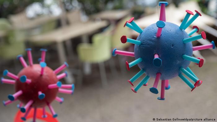 Игрушка в виде вириона вируса SARS-CoV-2 и пустые столы в ресторане во Франкфурте-на-Майне