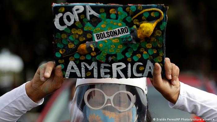 A woman holds a sign to protest against Brazil holding the Copa America in Brasilia.
