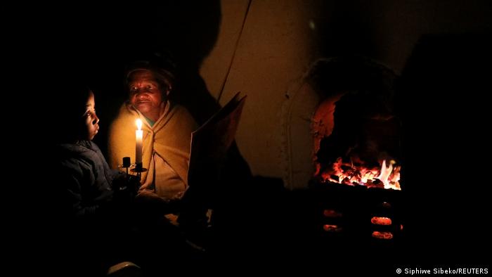 Urgroßmutter und Urenkelsohn sitzen im Schein einer Kerze an einem offenen Kamin in Südafrika (Foto: REUTERS/Siphiwe Sibeko)