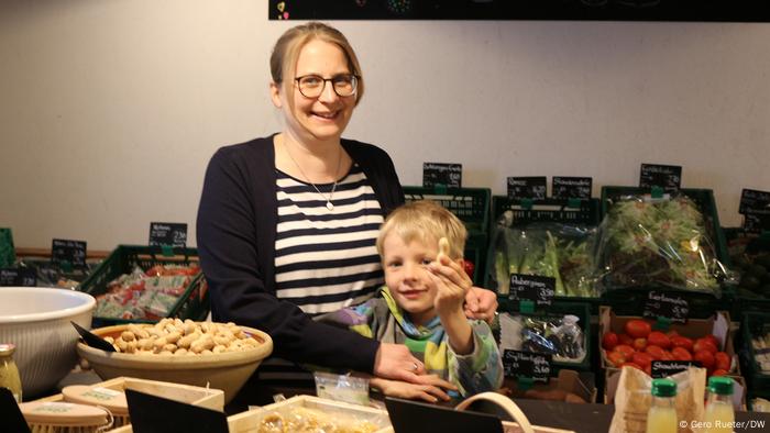 A woman poses with her son in their farm shop