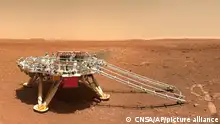 In this image released by the China National Space Administration (CNSA) on Friday, June 11, 2021, the landing platform with a Chinese national flag and outlines of the mascots for the 2022 Beijing Winter Olympics and Paralympics on Mars is seen from the rover Zhurong. China on Friday released a series of photos taken by its Zhurong rover on the surface of Mars, including one of the rover itself taken by a remote camera. (CNSA via AP)