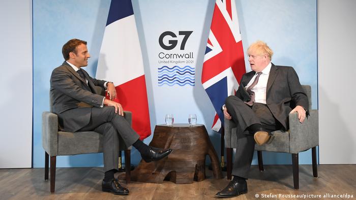 French President Emmanuel Macron (l) sits in a gray chair facing UK Prime Minister Boris Johnson (r)