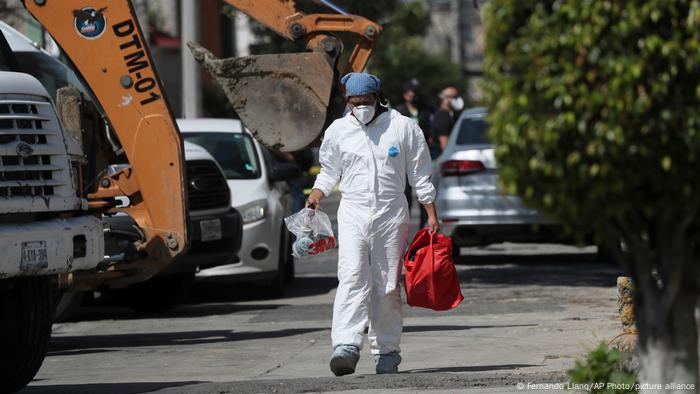 Un investigador forense lleva equipo fuera de la casa donde la policía encontró huesos bajo el suelo en el municipio de Atizapán del Estado de México.