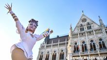 A participant gestures and poses in front of the parliament building in Budapest on June 14, 2021, during a demonstration against the Hungarian government's draft bill seeking to ban the promotion of homosexuality and sex changes, which will be discussed by Hungarian MPs tomorrow. - The Hungarian ruling party of right-wing Prime Minister Viktor Orban on June 10, 2021 introduced legislative amendments seeking to ban the promotion of homosexuality and sex changes. The move was swiftly denounced by Amnesty International, Budapest Pride and three other rights groups who compared the Fidesz party proposals to a similar law in Russia which punished acts of homosexual propaganda aimed at young people. If the Hungarian move becomes law it would effectively ban educational programmes and publicity of LGBT groups, according to the 11-page document seen by AFP. (Photo by GERGELY BESENYEI / AFP)