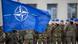 NATO flag with troops in the background NATO flag with troops in the background