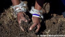 A woman with animal skin on her hands inspects the soil as fortune seekers flock to the village after pictures and videos were shared on social media showing people celebrating after finding what they believe to be diamonds, in the village of KwaHlathi outside Ladysmith, in KwaZulu-Natal province, South Africa, June 14, 2021. REUTERS/Siphiwe Sibeko