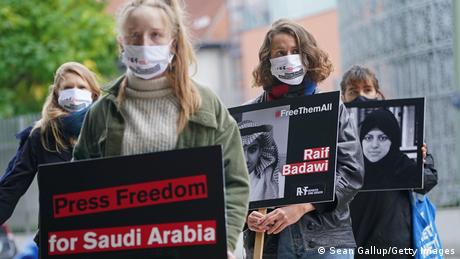Protesters from Reporters Without Borders hold a sign showing imprisoned Saudi Arabian blogger Raif Badawi