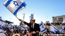 Israeli lawmaker Itamar Ben Gvir carries an Israeli flag as he dances together with others by Damascus gate just outside Jerusalem's Old City June 15, 2021. REUTERS/Ronen Zvulun