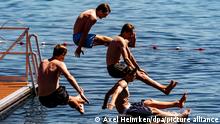 16.06.2021, Vier junge Männer springen von einer Schwimmplattform aus in einen zum Schwimmen abgesperrten Bereich der Kieler Förde. Auch im Norden startet der Sommer mit großer Hitze durch.