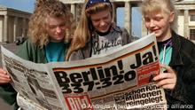 Am Brandenburger Tor in Berlin informieren sich Jugendliche am 23. Juni 1991, einen Tag nach der Abstimmung im Deutschen Bundestag über den Regierungssitz, in einer Zeitung. Mit 338 gegen 320 Stimmen hatten sich die Abgeordneten für Berlin als künftigen Regierungssitz entschieden.