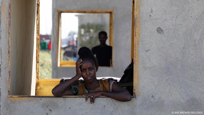An Ethiopian woman stands at a window of a temporary shelter at the Village 8 refugee transit camp