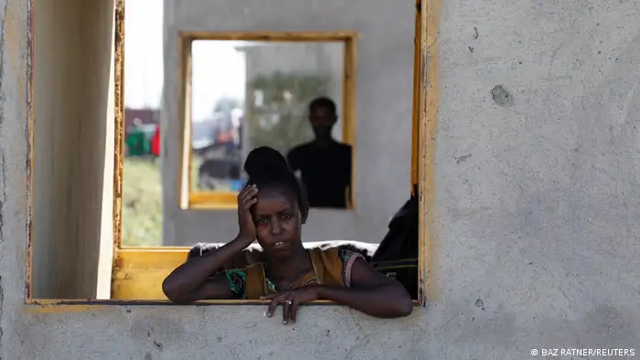 An Ethiopian woman stands at a window of a temporary shelter at the Village 8 refugee transit camp