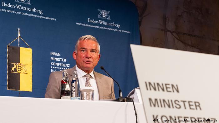 Baden-Württembergs Innenminister Thomas Strobl steht am Rednerpult. Im Hintergrund steht auf einer blauen Wand der Anlass der Veranstaltung: die Innenministerkonferenz.