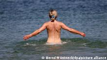 Eine Frau geht an einem FKK-Abschnitt des Ostseebades ins Wasser. An den Ostseestränden von Rostock gibt es großzügige und gekennzeichnete FKK-Bereiche. (Zu dpa An Ost- und Nordsee: FKK bietet nur noch wenig Anlass zum Streit) +++ dpa-Bildfunk +++