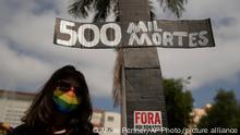 A woman, wearing a protective face mask, holds a sign in the shape of a cross with a message that reads in Portuguese;500 k deaths, during a protest against Brazilian President Jair Bolsonaro and his handling of the pandemic and economic policies protesters say harm the interests of the poor and working class, in Cuiaba, Brazil, Saturday, June 19, 2021. Brazil is approaching an official COVID-19 death toll of 500,000 — second-highest in the world. (AP Photo/Andre Penner)