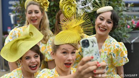Women wearing designer hats taking a selfie.