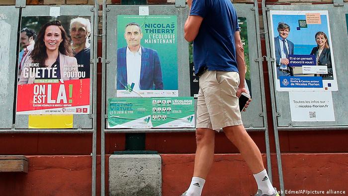 A man walks by posters advertising the French regional election