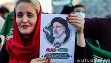 A woman holds a picture of Iran's newly-elected president Ebrahim Raisi as supporters celebrate his victory in Imam Hussein square in the capital Tehran on June 19, 2021. (Photo by ATTA KENARE / AFP)