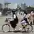 Women wearing face masks ride a bicycle in South Korea