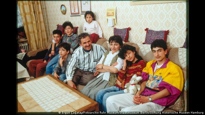 A family of eight sitting on a sofa. 