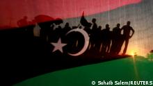 FILE PHOTO: Libyans are seen through a Kingdom of Libya flag during a celebration rally in front of the residence of Muammar Gaddafi at the Bab al-Aziziyah complex in Tripoli September 13, 2011. REUTERS/Suhaib Salem/File Photo