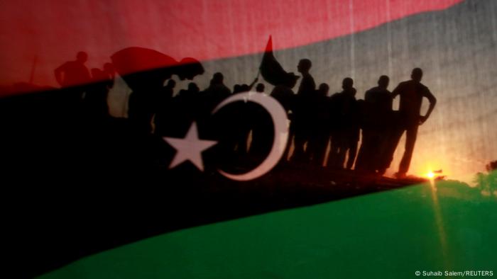 Menschensilhouetten hinter der libyschen Flagge