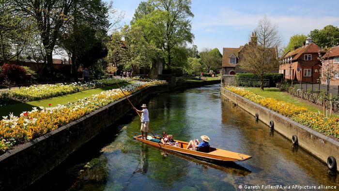Two people in a boat being punted by a third person on the Great Stour River in Canterbury, Great Britain
