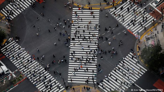Straßenkreuzung in Tokyo vor der Olympia mit Menschen, die die Straße überqueren.